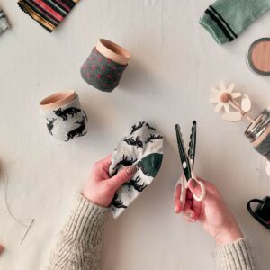Close up view of hands that holding scissors and socks - upcycling concept