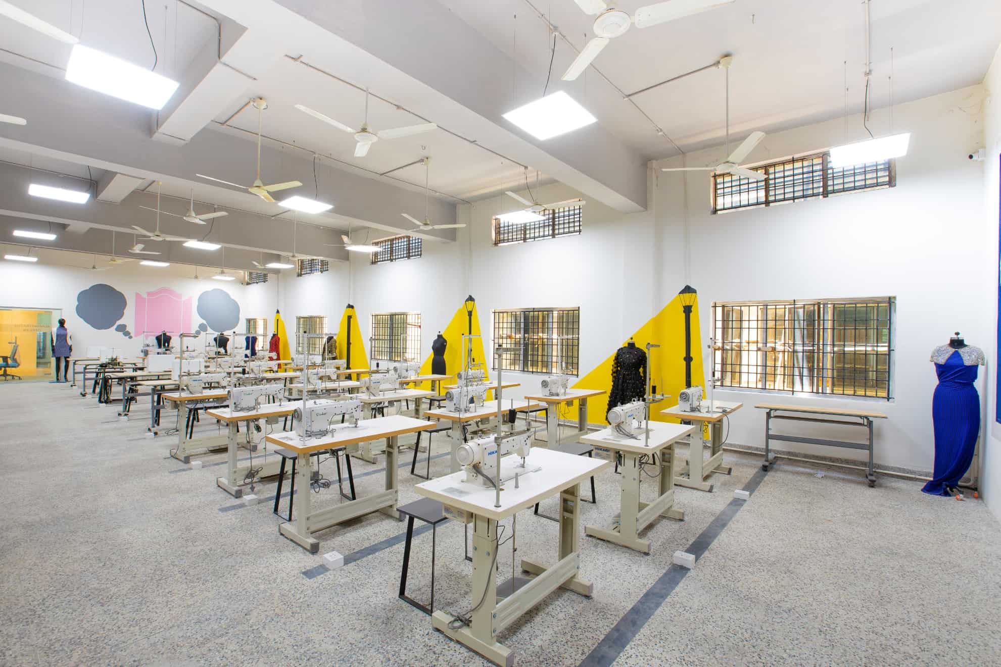 Side view of the airy and spacious fashion design studio with mannequins and rows of tables with attached sewing machines at a design college in Chennai