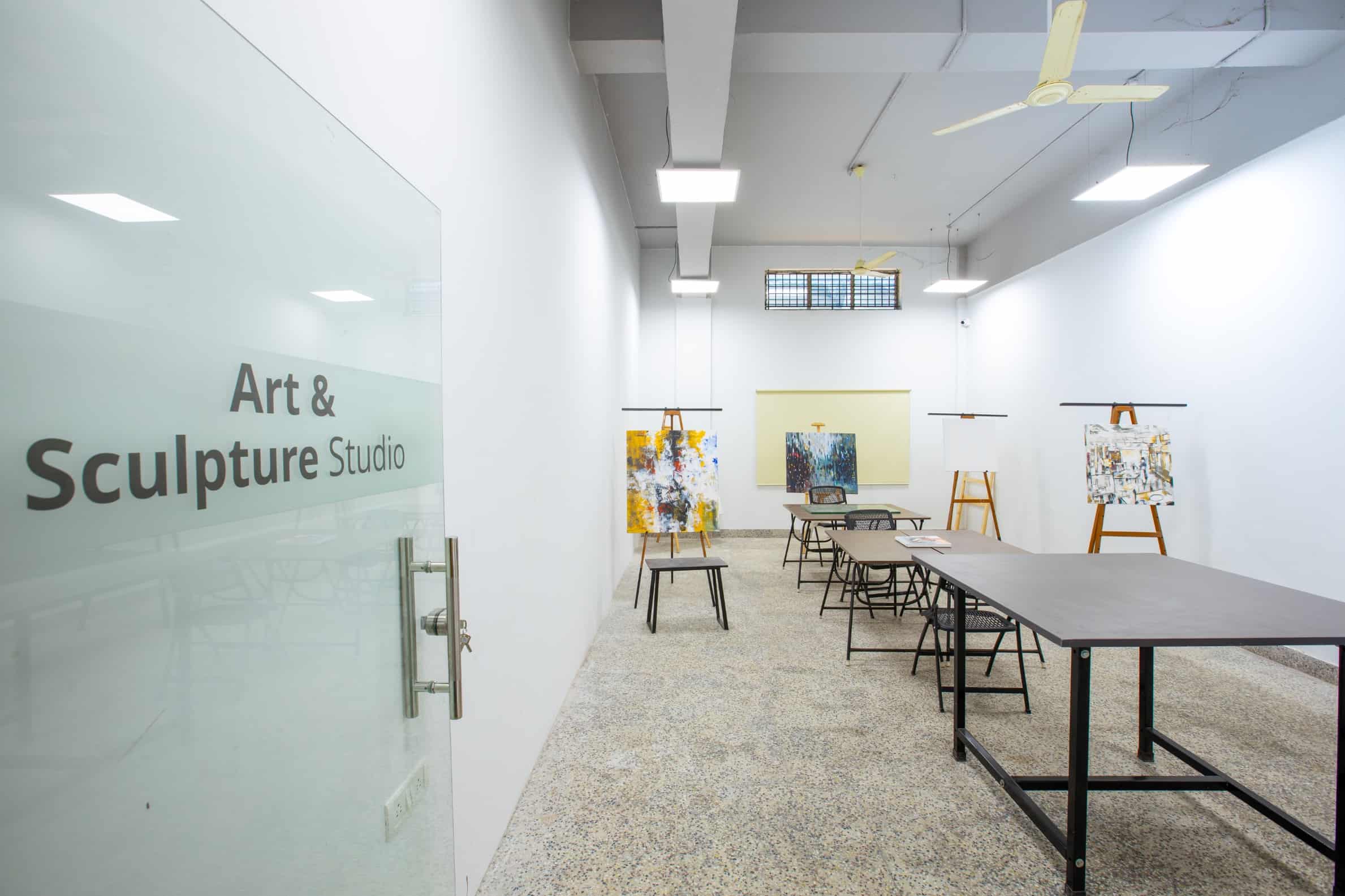 White walled art and sculpture studio room with tables and drawing board stand