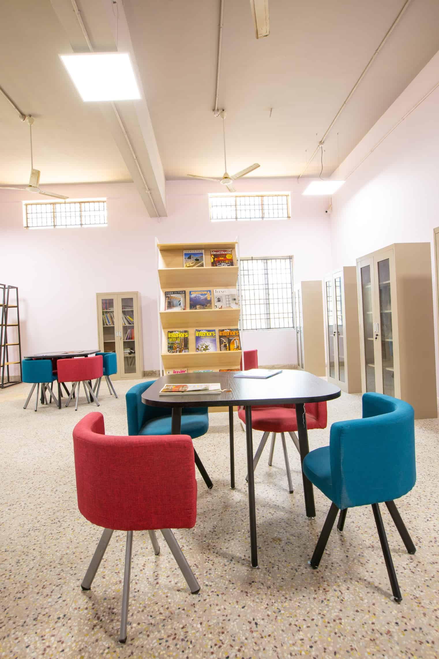 Library space with seating arrangements, books arranged in cupboards and open shelves