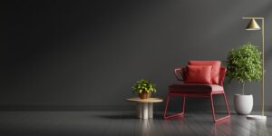 An interior design in dark tones with a red armchair against a black wall