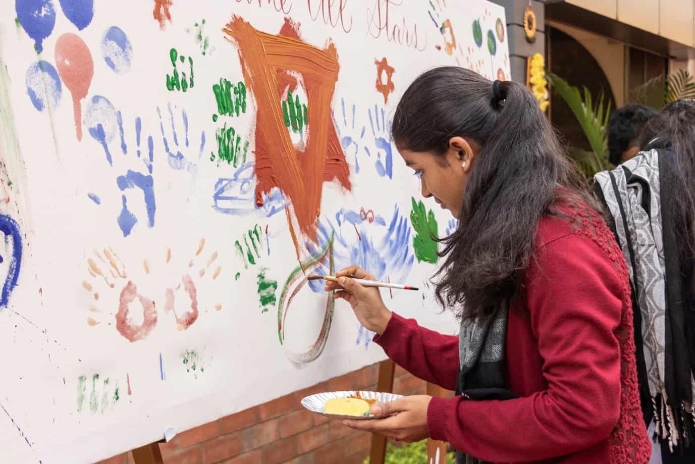 Young student of BFA college in chennai doing calligraphy and art work with color palette and brush on a board